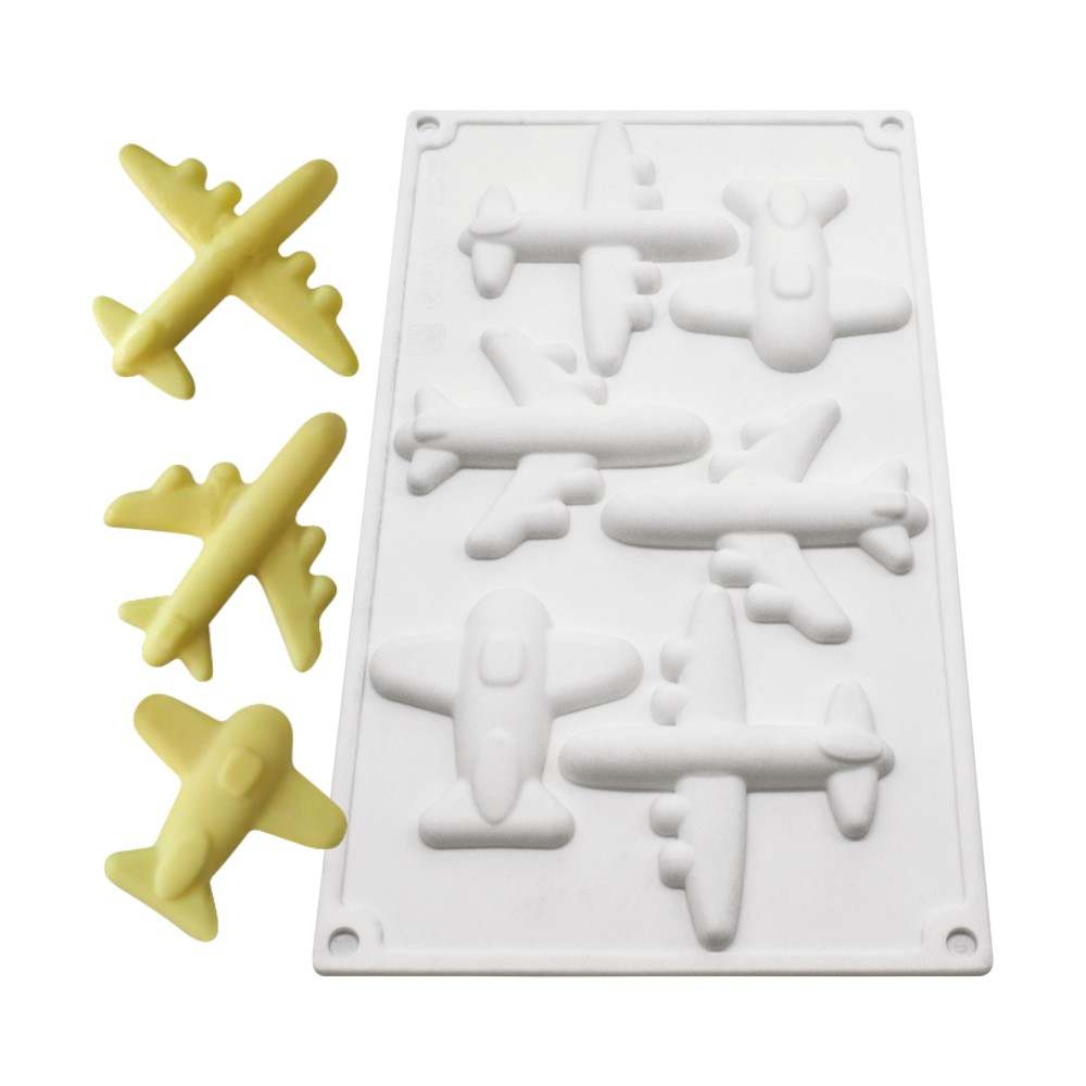 The image features a white silicone mold designed to create 3D airplane shapes. The mold displays several depressions in the form of various airplane designs, with a total of six shaped cavities visible. Alongside the mold, there are four finished airplane-shaped products in a yellow color, each resembling different styles of aircraft. The mold and the airplanes are arranged on a flat surface, highlighting the details of the mold&