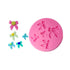 The image features a pink silicone mold shaped like a circle, with several bow-shaped impressions in various sizes. Surrounding the mold are multiple small decorative bows made of colored material, including pink, green, and blue shades. The bows vary in size and design, showcasing different color combinations and embellishments, adding a playful and decorative touch.