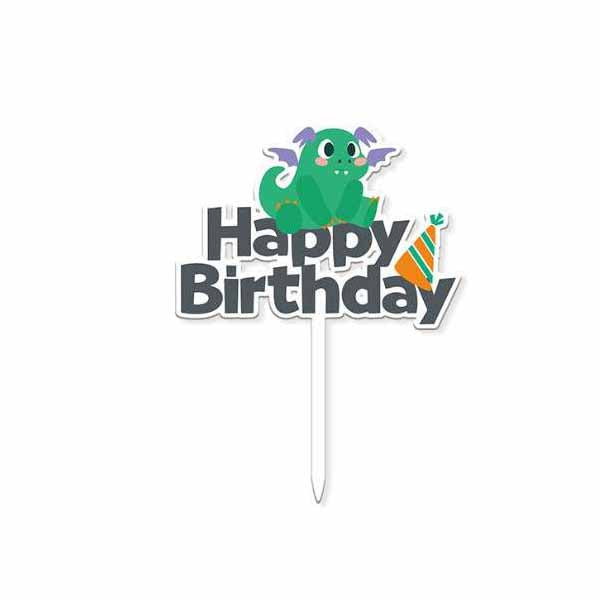 A colorful "Happy Birthday" cake topper featuring a cute green dragon with purple wings sitting on top of the word "Birthday." The topper includes a decorative party hat with orange and green stripes alongside the text. It is mounted on a white stick for insertion into a cake.