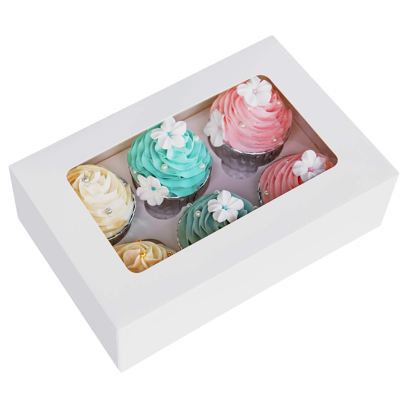 A white cupcake box containing six cupcakes is shown. The box features a clear window on the top, allowing a view of the cupcakes inside. The cupcakes have decorative frosting in pastel colors: two pink, two blue, one yellow, and one purple. Each cupcake is topped with small white flowers and embellishments, including tiny pearls. The overall presentation is cheerful and suitable for a special occasion.