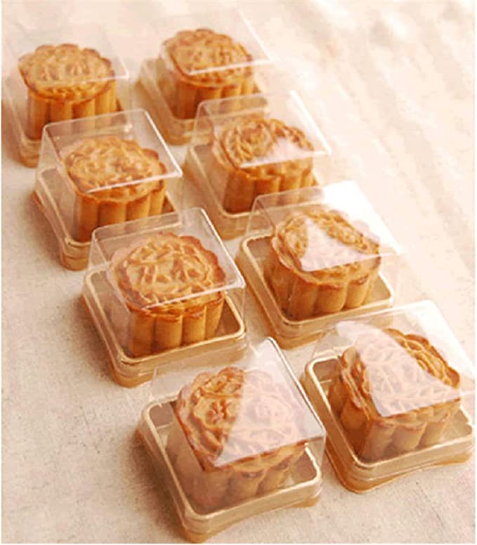 A row of eight mini mooncakes, each individually packaged in clear plastic boxes. The mooncakes have a decorative top and a round shape, resting on a light-colored surface.