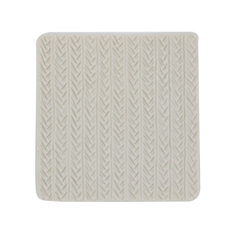 A square silicone mold with a textured surface resembling a knitted pattern. The mold is off-white in color and features raised lines and shapes that mimic the appearance of knit stitches.
