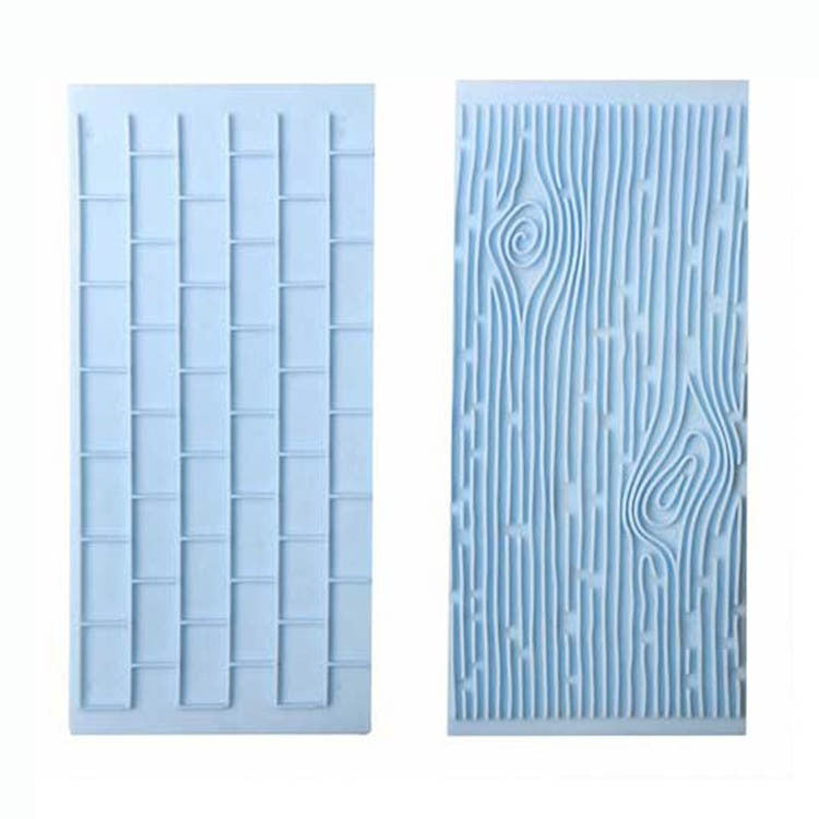 Two impression molds are displayed side by side. The left mold features a pattern resembling a brick wall, with rectangular shapes arranged in a grid format. The right mold has a design that resembles tree bark, with flowing lines and textures mimicking the natural pattern of wood grain. Both molds are made of light blue material.