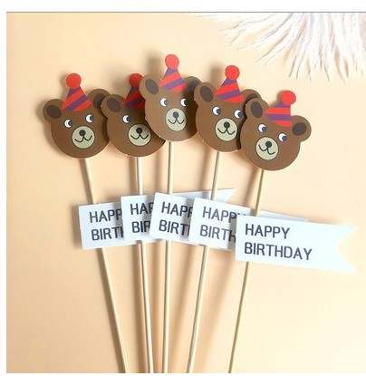 The image displays a set of five cake toppers featuring bear heads with party hats. Each bear has brown fur and a friendly expression. Alongside the bear toppers, there are two flags that read "HAPPY BIRTHDAY" in bold letters. The toppers are mounted on wooden sticks, suitable for decorating a birthday cake. The overall design is colorful and festive, ideal for a birthday celebration.