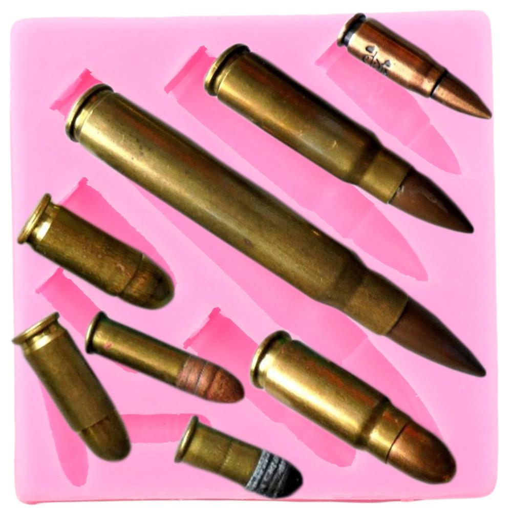 The image shows a pink silicone mould shaped like various bullets. The mould features several bullet forms of different sizes and shapes, with metallic finishes resembling brass. The bullets are positioned in various angles and arrangements within the mould, which is designed for creating bullet-shaped items, possibly for baking or crafting purposes.