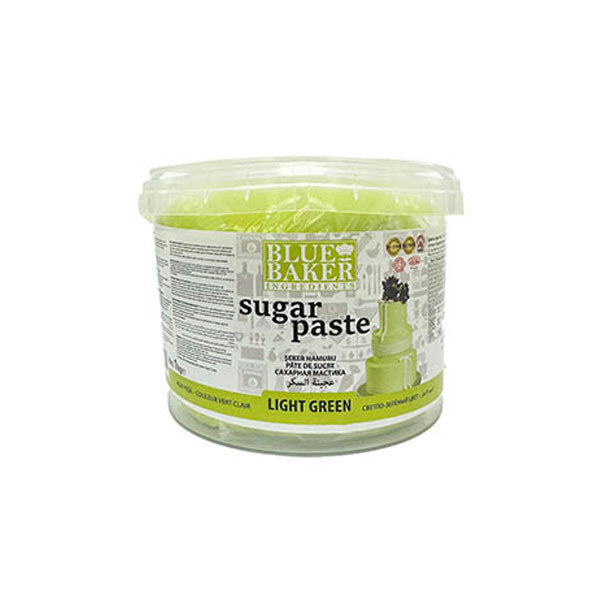 A clear plastic tub of light green sugar paste labeled "Blue Baker" is shown. The container has a lid and features a design with text that includes the product name "sugar paste," along with notes about its usage. The tub is prominently marked as "LIGHT GREEN." The label also includes various icons and small illustrations related to baking.