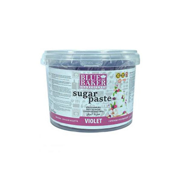 A transparent plastic container labeled "Blue Baker Sugar Paste" in violet color. The container weighs 1 kg and features colorful designs and icons, indicating it is suitable for cake decorating. The label includes usage instructions and product information in multiple languages, with images of decorated cakes on the front.