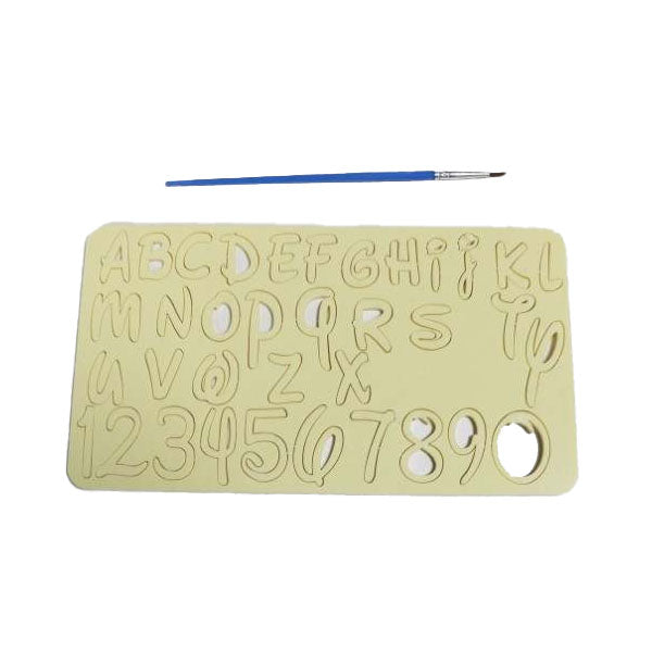 A light-colored acrylic stamping template featuring uppercase letters A to Z and the numbers 0 to 9, with decorative elements in the letters. A small blue paintbrush is placed diagonally above the template. The template has a circular cutout on one side for easy handling.