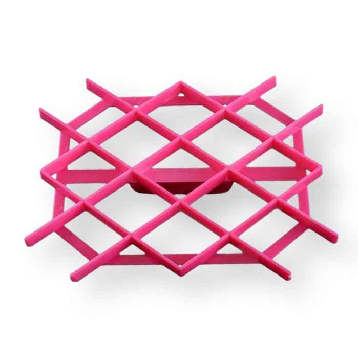 An image of a pink plastic cookie cutter designed to create quilt pattern designs on cookies. The cutter features a grid-like structure with horizontal and vertical lines intersecting to form a diamond design. It has a flat base and a raised edge for easy handling. The background is plain, emphasizing the cutter&