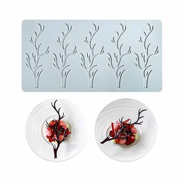 A silicone mold with six hollow branch-shaped cavities, designed for creating intricate edible decorations. Two plated desserts with chocolate branch designs are displayed below, demonstrating creative plating ideas.