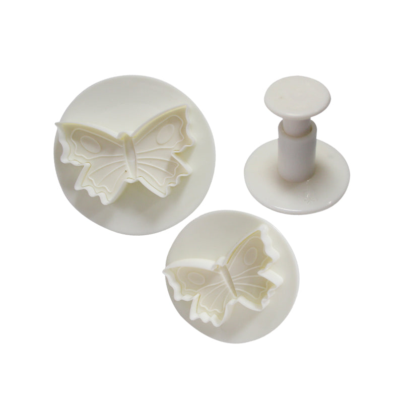 A set of three butterfly-shaped plunger cutters in white plastic. The set includes two circular cutters with raised butterfly designs and a plunger handle used for pressing out the shapes. The cutters are intricately detailed and vary slightly in size.