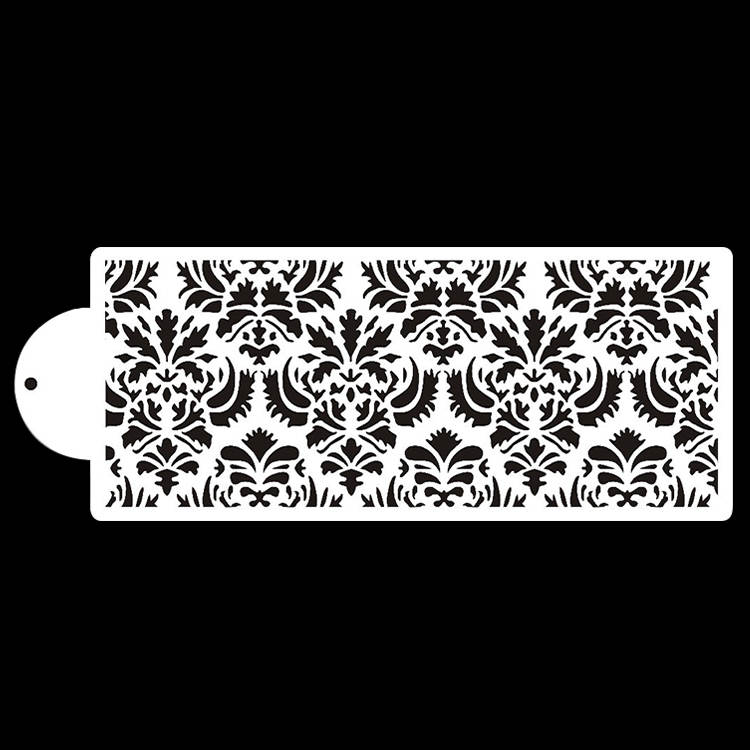 The image features a cake stencil named "cake stencil ct 15." It depicts an intricate, repeating pattern of floral and ornamental designs. The stencil is primarily white with a detailed black design, showing various shapes and motifs that create a lace-like appearance. The stencil has a rounded handle on one side for easy handling. The background is solid black, highlighting the contrast between the white stencil and the black design.