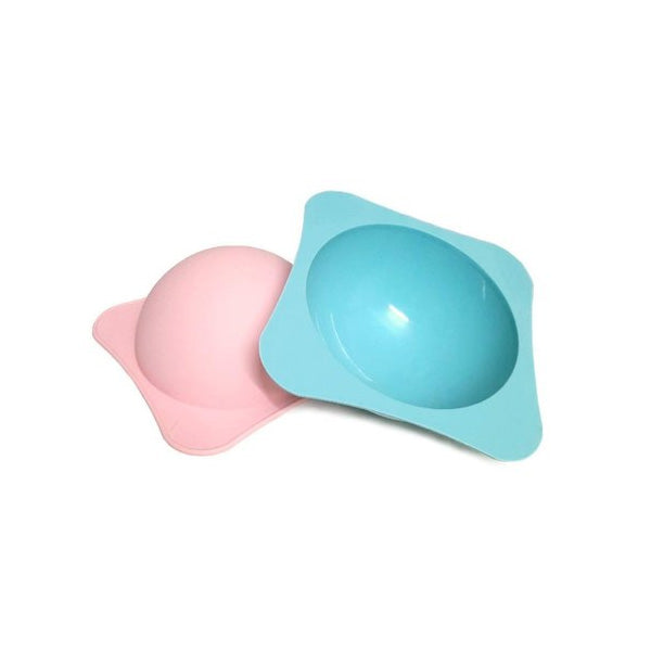 Two round piñata molds are shown in the image. One mold is pink and the other is blue, both constructed from a flexible plastic material. Each mold has a rounded shape with a flat base and is designed to create hollow piñatas. The pink mold is positioned in the foreground, while the blue mold is slightly behind and to the right.