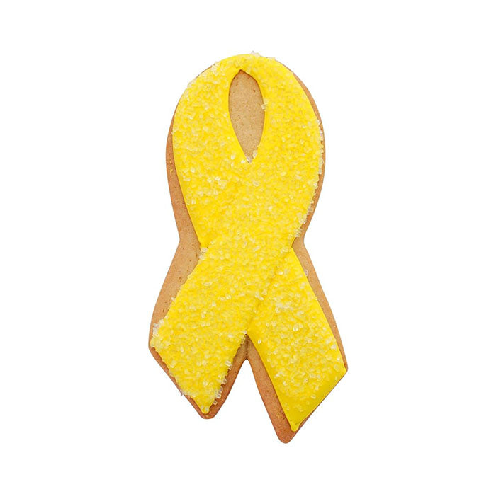 A yellow cookie shaped like an awareness ribbon, decorated with yellow icing and sprinkled with coarse sugar. The cookie has a golden-brown base and features the classic loop and tail design of a ribbon.