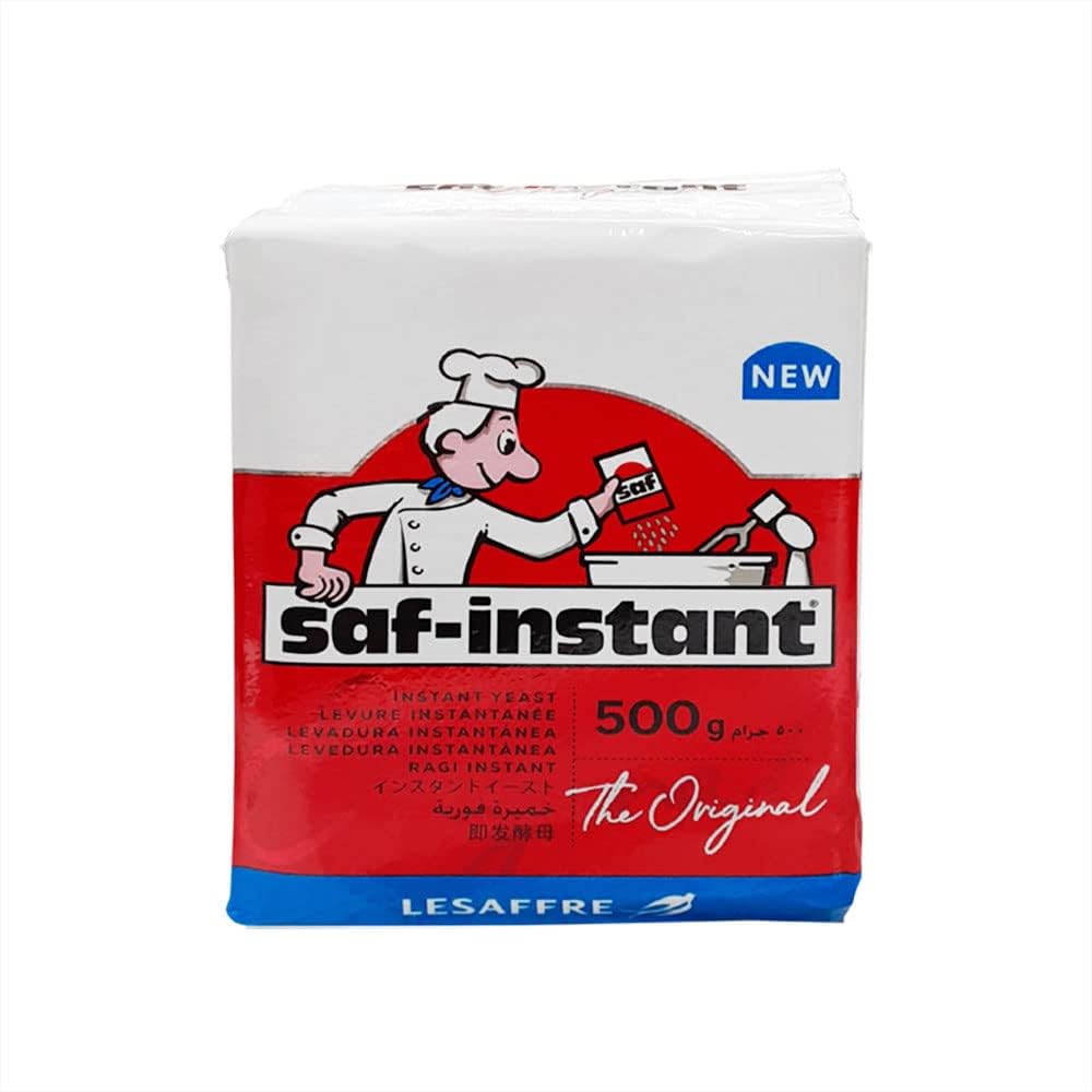 A packet of SAF Instant Active Dry Yeast, weighing 500g. The packaging features a colorful design with a chef character pouring yeast into a mixing bowl. The product name "saf-instant" is prominently displayed in bold letters, along with the words "Instant Yeast" in multiple languages, and the phrase "The Original". The top corner has a "NEW" label, and the brand name "LESAFFRE" is featured at the bottom.