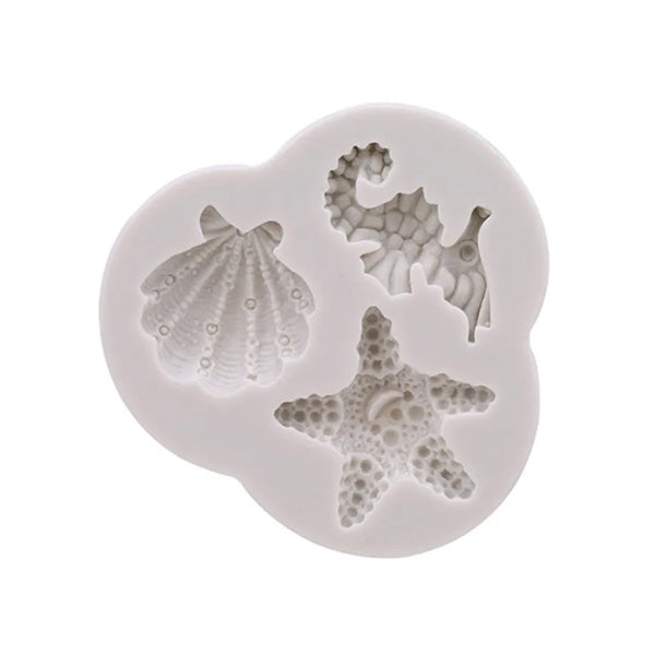 A white silicone mold featuring three ocean-themed designs: a scallop shell, a seahorse, and a starfish. The mold is shaped like a cloud, with each design distinctly detailed.