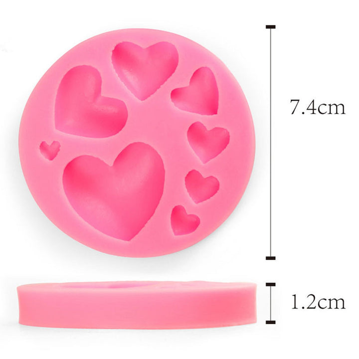 A pink silicone mould shaped like a circle with multiple heart cavities of varying sizes. The mould measures 7.4 cm in diameter and 1.2 cm in height.