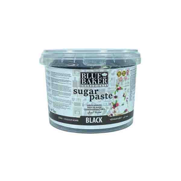 The image features a clear plastic tub of "Blue Baker Black Sugar Paste" with a 1kg capacity. The label displays the product name prominently, with the word "BLACK" indicated. The packaging includes various information and icons, and it shows decorative elements, suggesting its use for cake decorating.