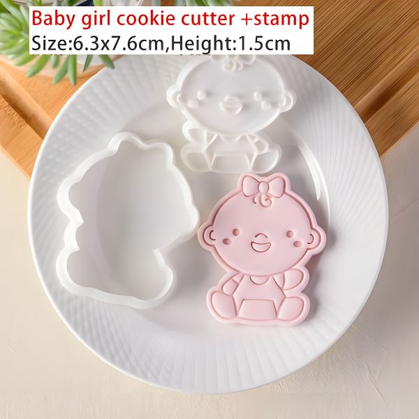The image shows a white plate with three cookie cutters and a stamp designed for making baby-themed cookies. The cookie cutters include a pink baby figure with a bow on its head, a white simple baby face design, and a white bear shape. The plate is placed on a light-colored surface, and there is a hint of greenery in the background. A text overlay indicates that the product is a "Baby girl cookie cutter stamp" with dimensions of 6.3 x 7.6 cm and a height of 1.5 cm.