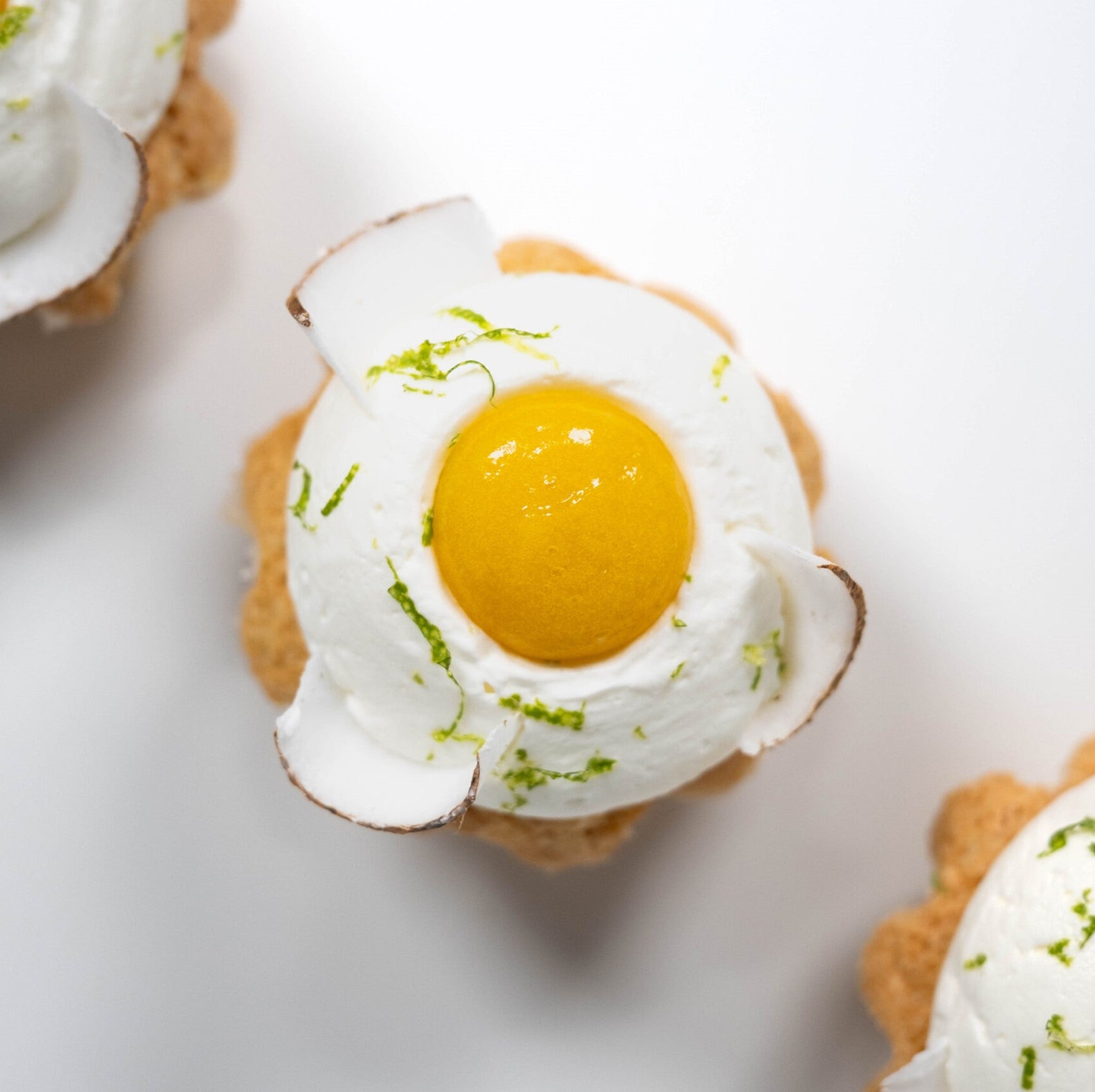 Three petite cakes, each adorned with an egg on top, displayed on a decorative platter.