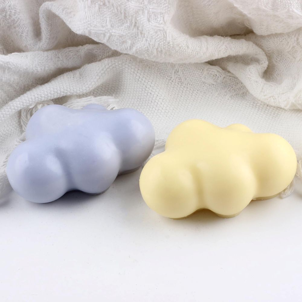 Two cloud-shaped objects, one purple and one yellow, on a textured fabric background.