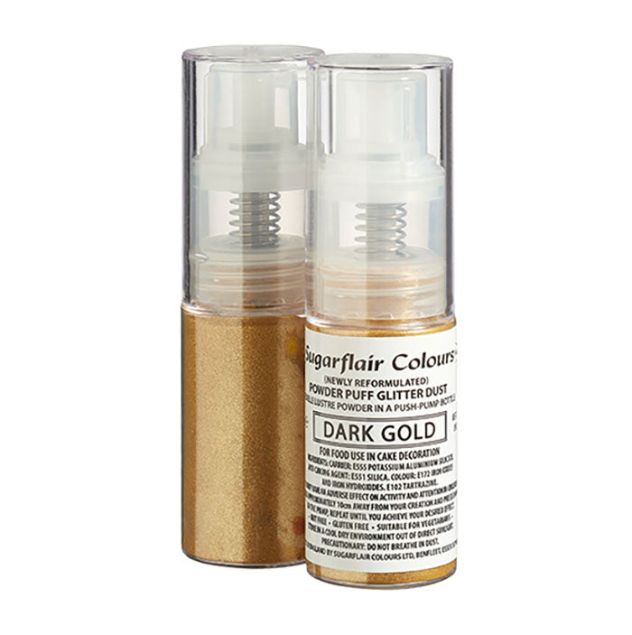 The image shows two transparent spray bottles containing dark gold edible glitter dust. One bottle is slightly behind the other. The front bottle has a label that reads "Sugarflair Colours," along with details like "Powder Puff Glitter Dust" and "DARK GOLD." The label includes usage instructions for cake decoration and lists ingredients. The glitter dust in the bottles has a shimmery appearance, and the bottom part of each bottle is gold in color.