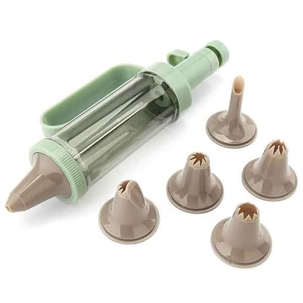The image features a cake decorator syringe kit. The kit includes a transparent syringe with a green handle and nozzle. Surrounding the syringe are five different piping nozzles, each with unique shapes on the tip for varied cake decoration. The nozzles are brown and include designs suitable for creating different frosting patterns. The setup is laid out on a plain background.