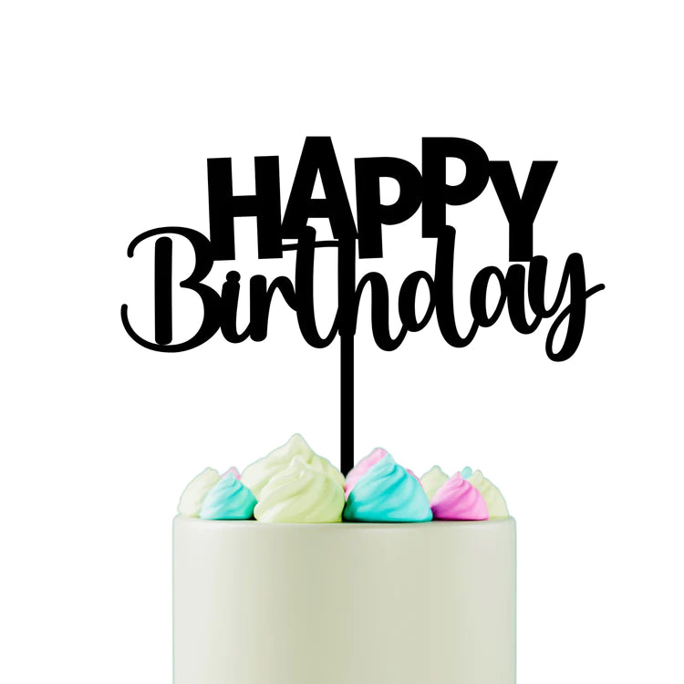 A cake with a smooth white frosting at the top, decorated with pastel-colored meringue peaks in green, pink, and white. Atop the cake is a black acrylic cake topper that reads "HAPPY Birthday" in a playful font, with the word "HAPPY" in uppercase letters and "Birthday" in a cursive script. The background is plain white.