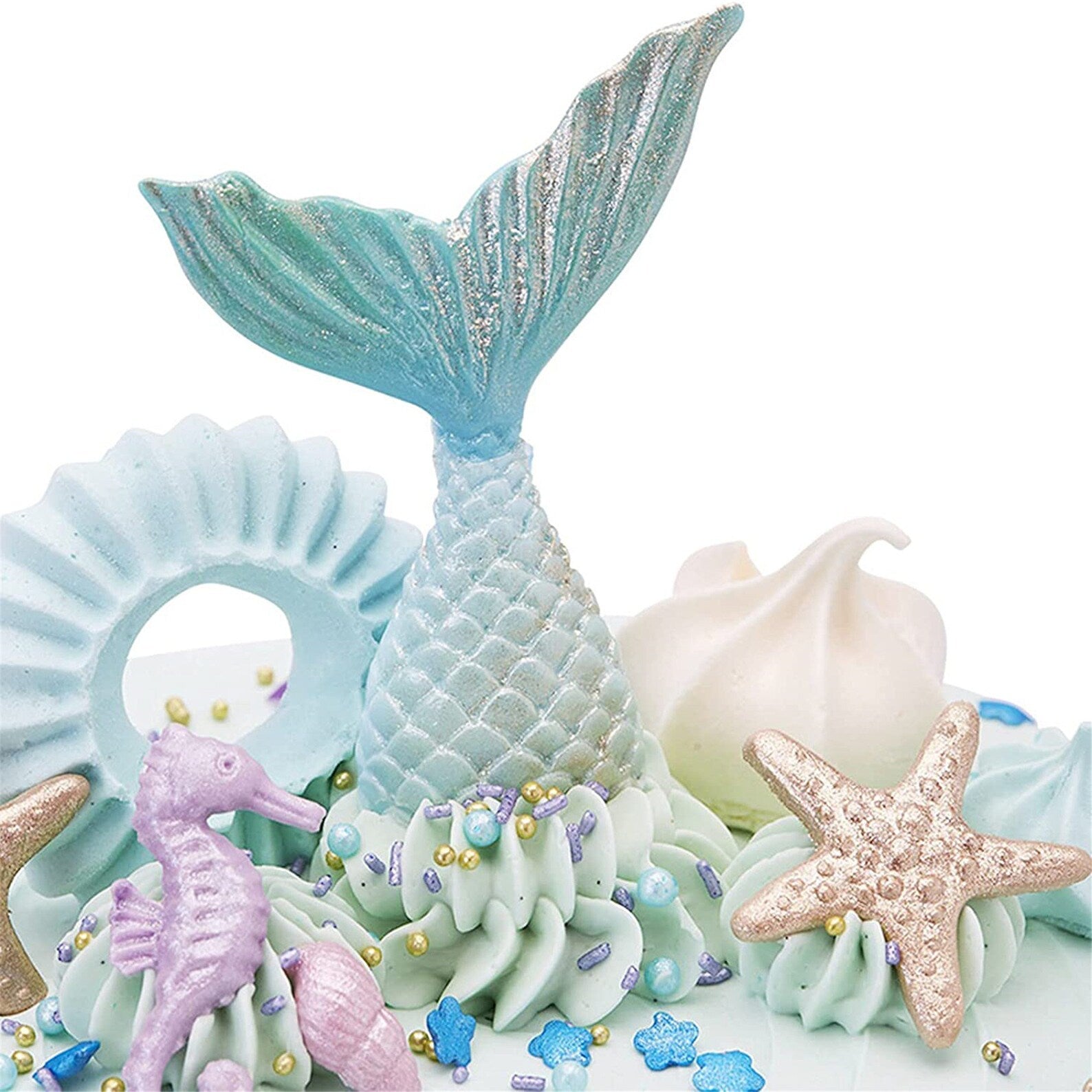 A decorative cake featuring various ocean-themed elements, including a blue and glittery mermaid tail, a light blue shell-shaped piece, a purple seahorse, a beige starfish, and soft swirls of aqua-colored icing. The design incorporates colorful edible decorations like small beads and star-shaped sprinkles.