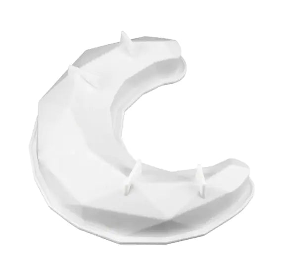 A white silicone mold shaped like a three-dimensional crescent moon, featuring a geometric, faceted design. The mold has small triangular protrusions on its surface for added detail.