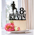 A decorated cake featuring a cream-colored frosting is topped with a black personalized soccer player cake topper. The topper includes the text "8th BIRTHDAY KEVIN," and a silhouette of a soccer player in a standing pose, one foot on a soccer ball. Surrounding the base of the topper are vibrant flowers, including pink peonies and green accents. The cake is presented on a decorative white plate. The background suggests a bright and cheerful indoor setting.