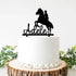 A personalized cake topper featuring a silhouette of a horse and rider is placed on top of a round white cake. The rider is depicted in a mounted position, and below the silhouette, the name "Adele" is written in a flowing script. The cake is set on a wooden slice and surrounded by greenery.