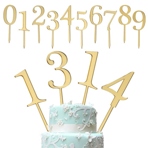 The image features a set of golden cake toppers arranged at the top and on a decorated cake. The top section displays numerical toppers from 0 to 9, while the bottom section showcases the numerals 1, 3, and 4 inserted into a light blue, multi-tiered cake adorned with white floral decorations and intricate designs. The cake has a smooth finish, and the cake toppers are prominently featured, adding a celebratory touch.