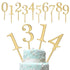 The image features a set of golden cake toppers arranged at the top and on a decorated cake. The top section displays numerical toppers from 0 to 9, while the bottom section showcases the numerals 1, 3, and 4 inserted into a light blue, multi-tiered cake adorned with white floral decorations and intricate designs. The cake has a smooth finish, and the cake toppers are prominently featured, adding a celebratory touch.