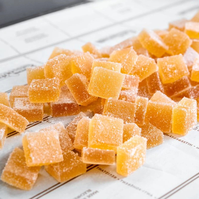 A collection of orange gummy bears stacked together on a white background.