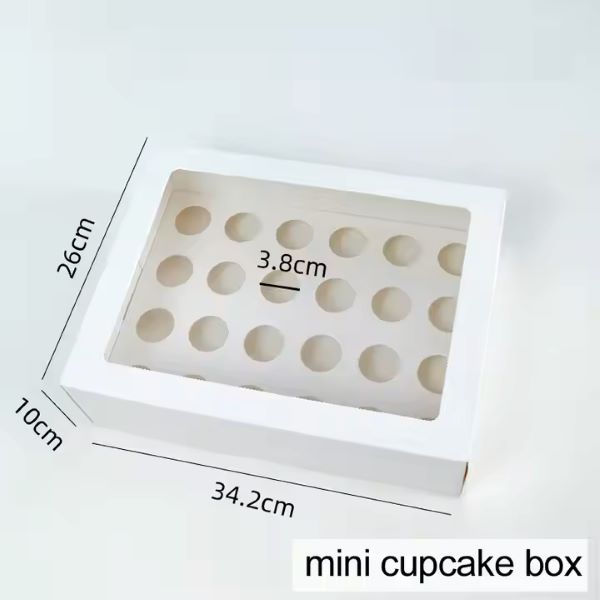 An image of a rectangular white box designed to hold mini cupcakes. The box features a transparent window on top, allowing visibility of the interior, which has 24 evenly spaced circular holes for placing cupcakes. Dimensions are shown: 34.2 cm in length, 26 cm in width, and 10 cm in height, with individual holes measuring 3.8 cm in diameter. The text at the bottom states "mini cupcake box."