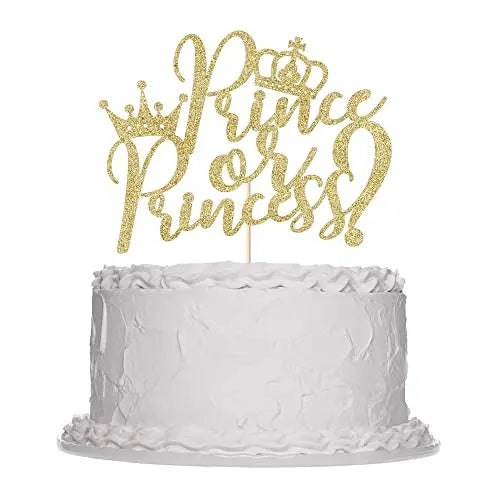 A simple white cake with a textured frosting, topped with a gold glittery cake topper that reads "Prince or Princess!" in an elegant script font, adorned with crowns.