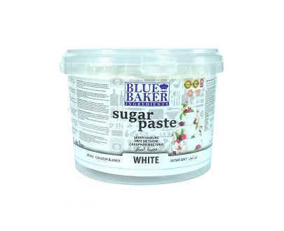 The image shows a clear plastic container of white sugar paste. The container is labeled "BLUE BAKER" with the product name "sugar paste" prominently displayed. The front of the container includes details about the product, such as its color ("WHITE") and features illustrations of cakes decorated with sugar paste. The container is round and has a secured lid.