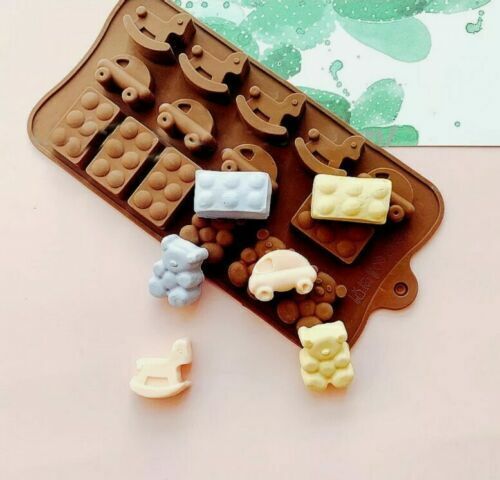 The image features a silicone mould in the shape of various baby toys, including rocking horses, bears, cars, and building bricks. The mould is brown and contains several cavities for each shape. Surrounding the mould are colorful finished products shaped like a blue bear, a yellow car, a light pink rocking horse, and brown building bricks. The background features a subtle green and white design.