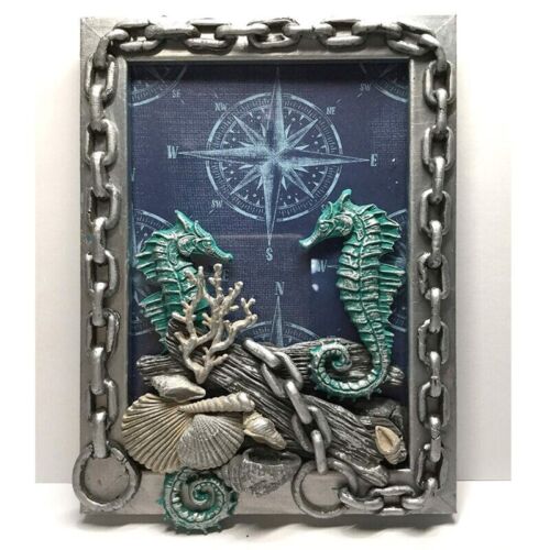 The image depicts a silicone mold designed for creating chain-shaped items. The mold features intricate designs, including two textured seahorses in shades of teal, several seashells, and coral shapes. The background showcases a compass graphic, adding a nautical theme. The frame of the mold is adorned with a silver chain motif, enhancing its decorative appeal. Overall, the mold combines various marine elements with a metallic finish.