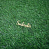 A wooden cake topper that reads "Soulmates" in an elegant cursive font, placed on a textured green grass background.