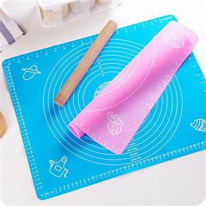 An image of a fondant silicone rolling mat is shown. The mat is bright blue and features printed measurements and design markings useful for baking. A pink silicone rolling mat is partially rolled up on top of the blue mat. Next to the mats, there is a wooden rolling pin. The background is neutral and highlights the mats and rolling pin.