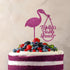 A layered cake with purple layers and white frosting topped with a variety of fresh berries, including strawberries, blueberries, and blackberries. Atop the cake is a pink glittery cake topper in the shape of a stork holding a bag, accompanied by the text "Molly&