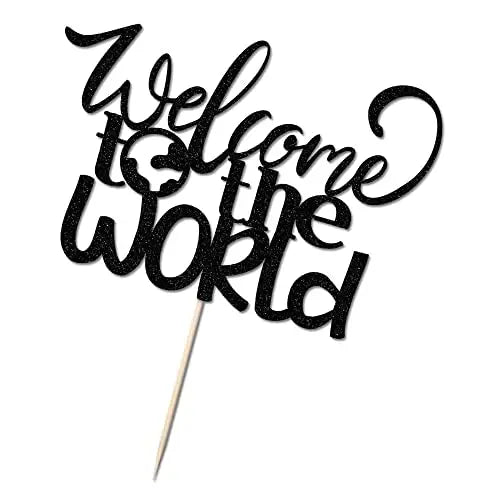 A black cardstock cake topper featuring the phrase "Welcome to the World" in a decorative, cursive font. The words are artistically arranged, with a small globe graphic integrated into the text. The topper is attached to a wooden stick for easy placement on a cake. The overall design has a sparkly appearance.
