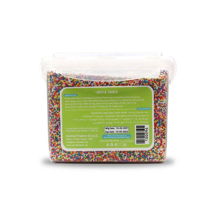 A clear plastic container filled with colorful confetti sugar sprinkles. The back of the container features a green label with product information, including ingredients, manufacturing date, and expiration date. The sprinkles are a mix of different colors, adding a vibrant appearance.