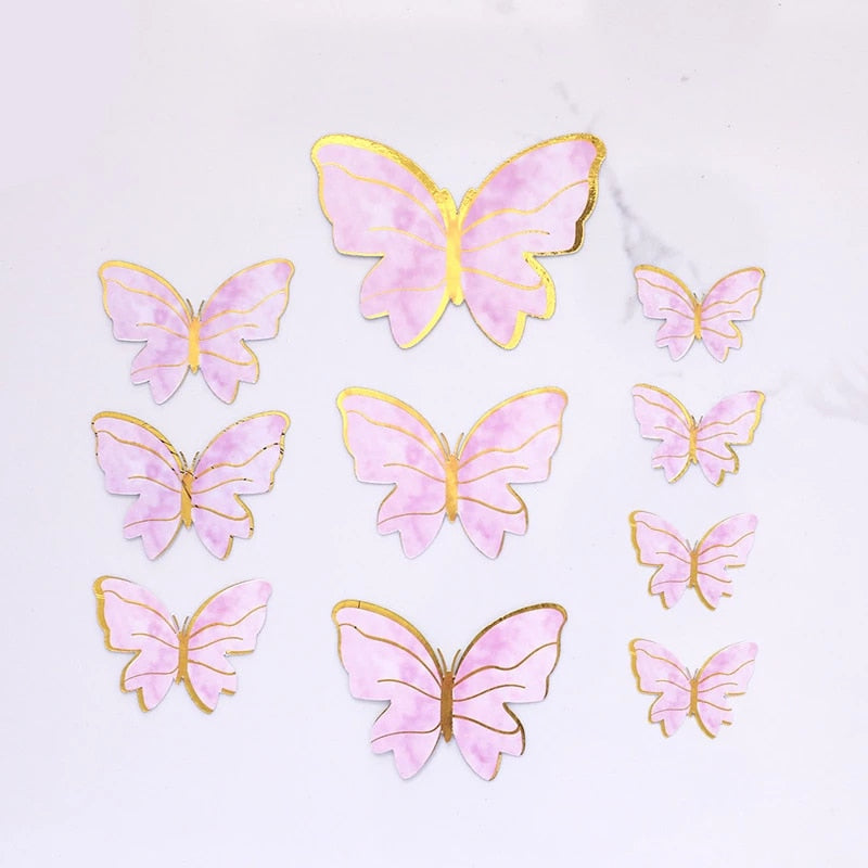 A set of five butterfly cake toppers in various sizes, featuring a pink and gold design. The butterflies have delicate outlines and a marbled pink appearance with metallic gold accents around the wings. The arrangement includes one large butterfly at the top and several smaller butterflies in a cluster below it. The background is plain and light-colored.