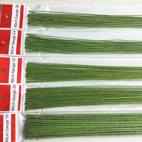 Image shows multiple packs of green floral wire, each containing several long, thin wires. The wires are arranged in rows, with labels indicating their gauges (from 18 to 26) and length (40 cm) on the packaging in red and white.