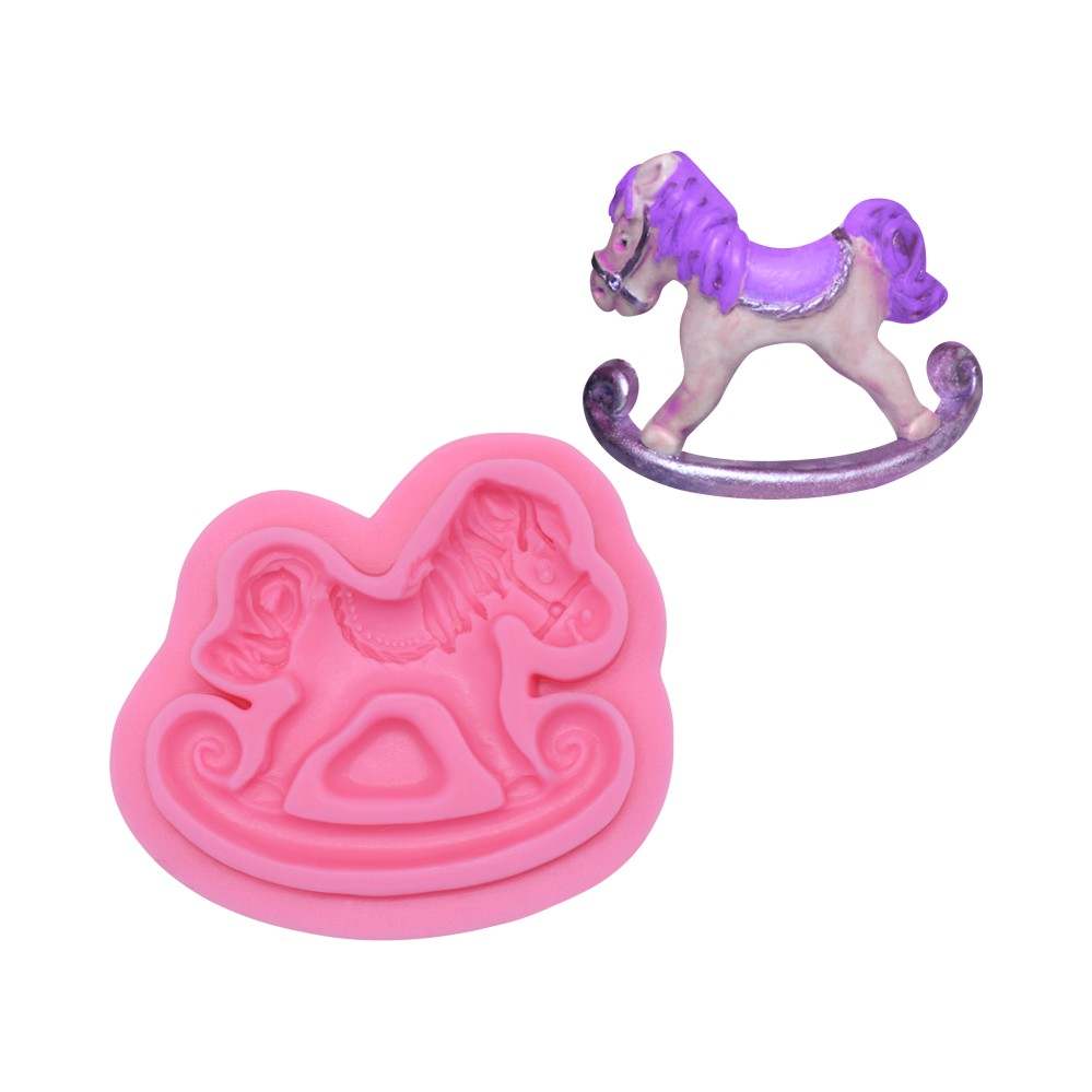 A pink silicone mould in the shape of a rocking horse sits next to a small decorative rocking horse figurine. The figurine is white with a purple mane and saddle, resting on a curved base.