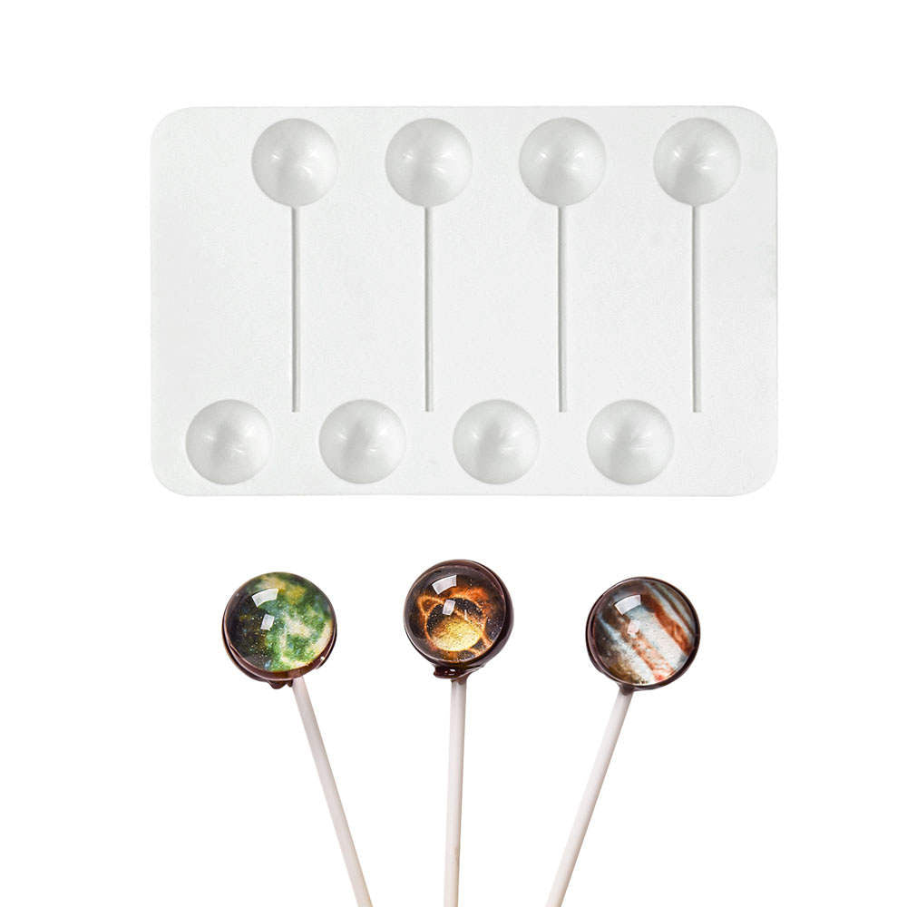 A white silicone mold for making lollipop balls, featuring six circular cavities with sticks attached. Below the mold, there are three lollipop balls on sticks, each showcasing different colorful designs resembling gemstones.