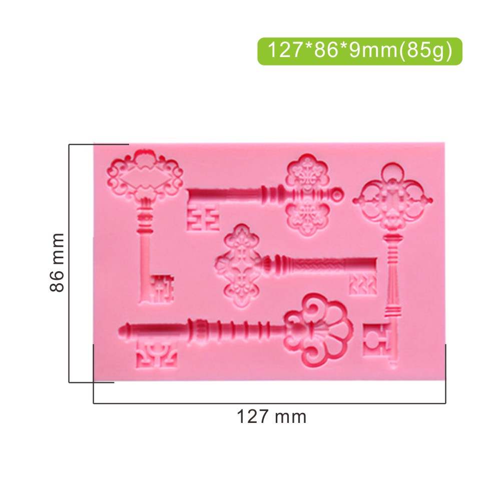 The image features a pink silicone mold designed for creating vintage antique key shapes. The mold includes several intricate key designs, each with decorative elements. Dimensions on the image indicate the mold is 127 mm by 86 mm, with a thickness of 9 mm, and it weighs 85 grams. The keys vary in style and detail, making it suitable for crafting decorative items.